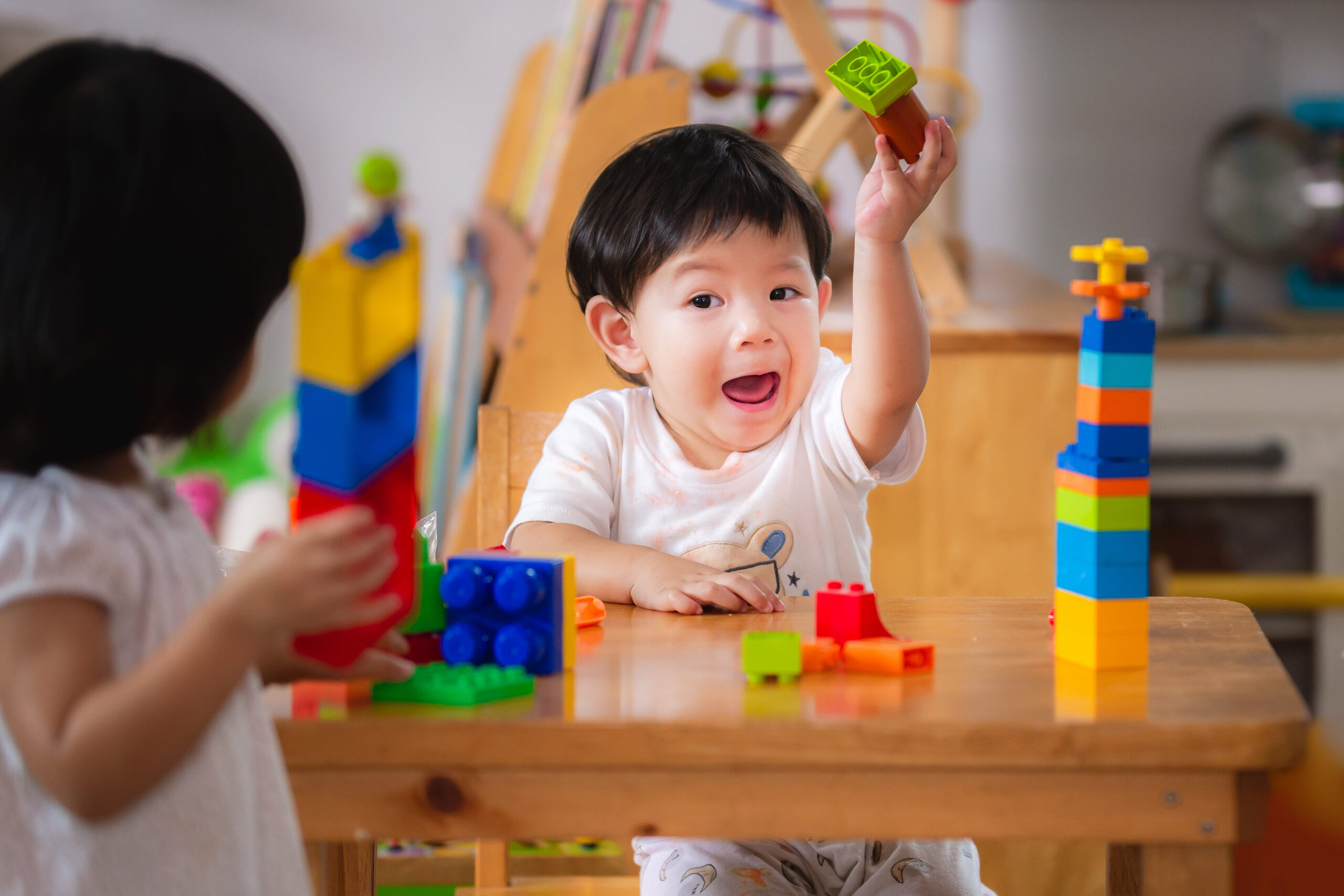 Stanmore College - Early Years. Baby age 1 years and 2 years old. Asian boy and girl playing with colorful plastic blocks.Children are learning to design and build from toys. Hand muscle development.