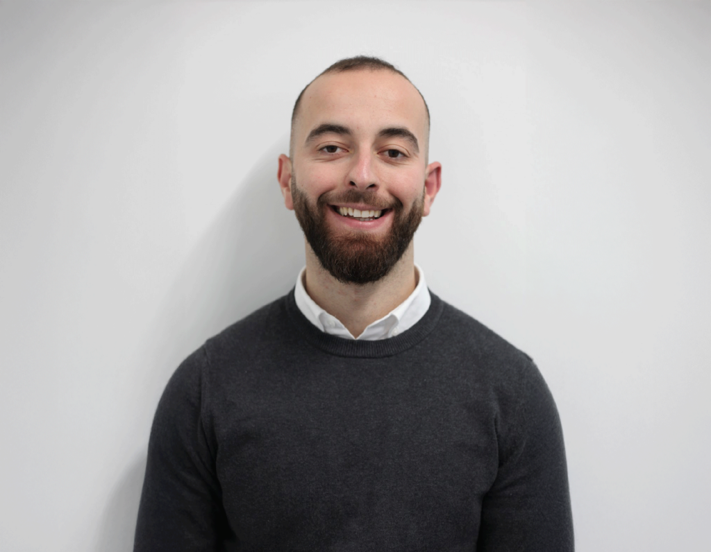 Fatjon Stanmore student smiling in front of plain background.