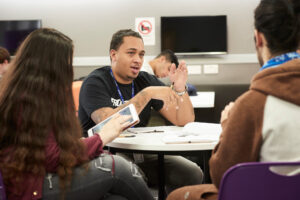 teacher talking to group of students around round table