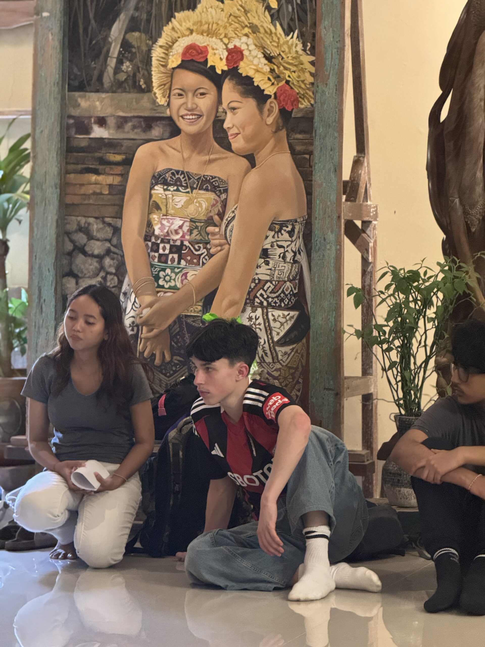 Students sitting in Art Gallery in Bali with two statues behind them