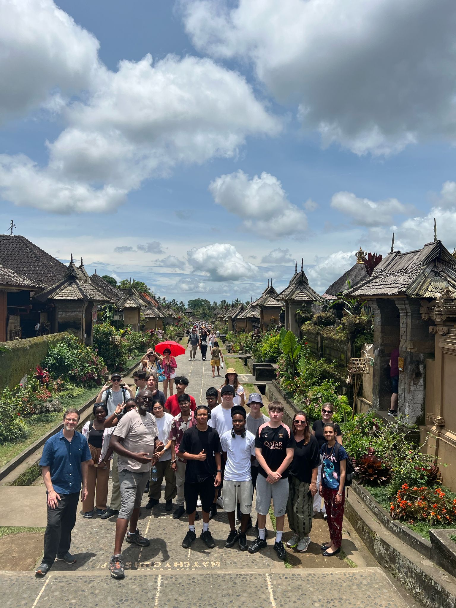 Students and staff in group in Bali with local houses in background.