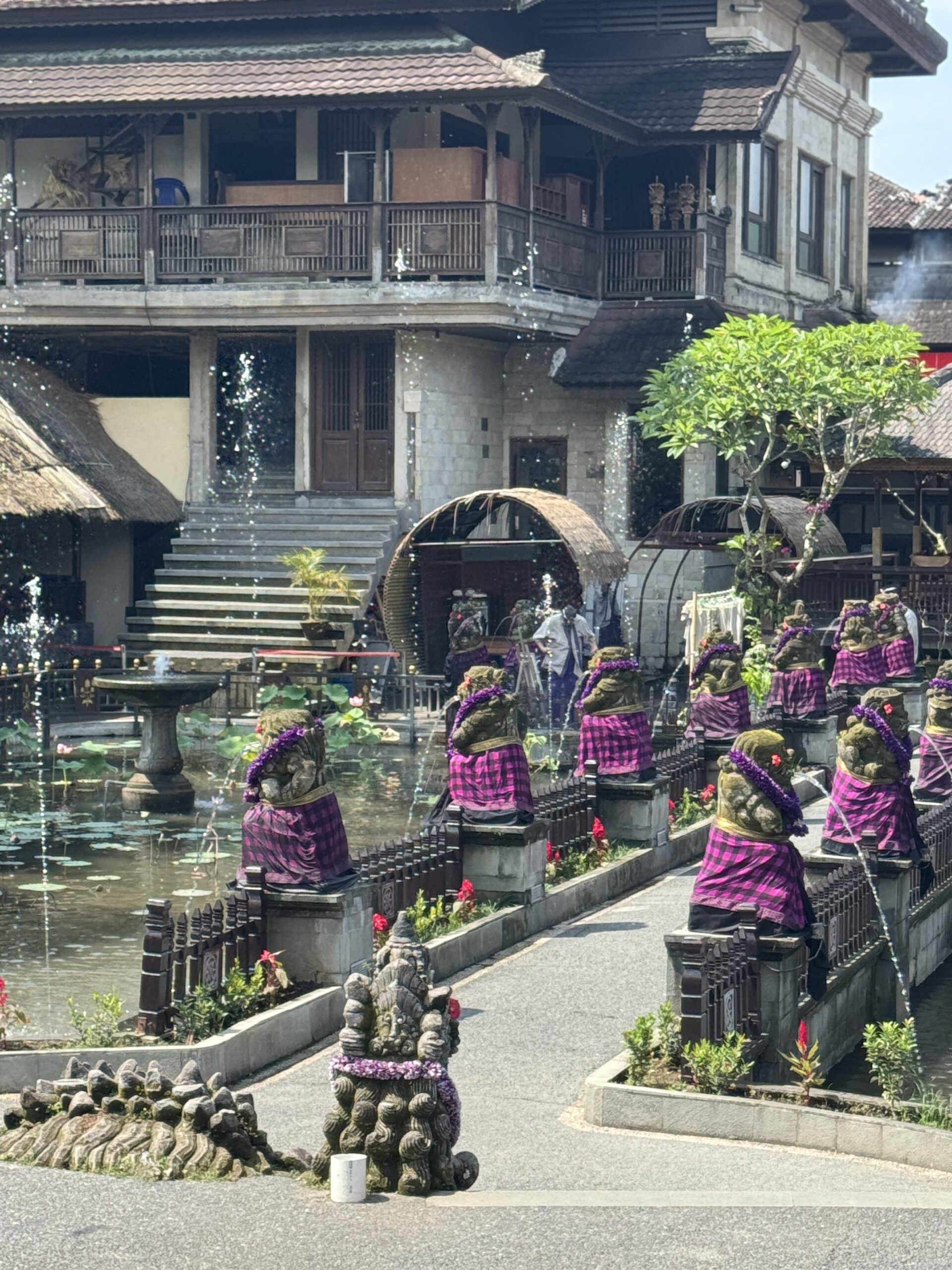Artefacts and statues with purple flowers at temple temple in Bali
