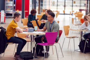 Stanmore College - Communal Area Of Busy College Campus With Students & teacher Working At Tables
