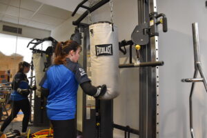 girl punching boxing bag in gym
