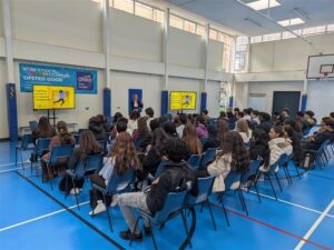 Group of students in sitting in a sports hall.