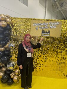 Ruhina Mehdi pointing to sign at London Building Expo
