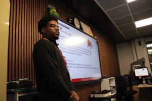 Anthony James presenting in front of screen.