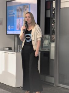 Woman giving talk with microphone and screen behind her.