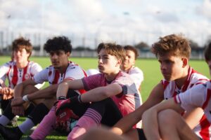 Brentford Football Club student group sitting at football pitch